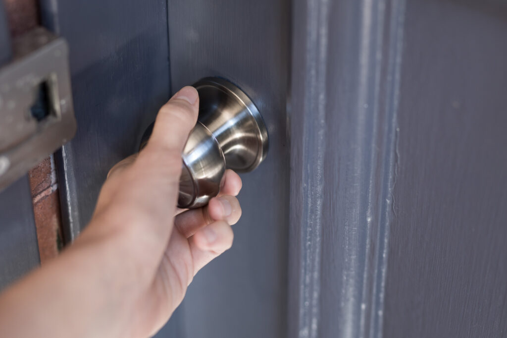 Hand turning front door knob during lock change service