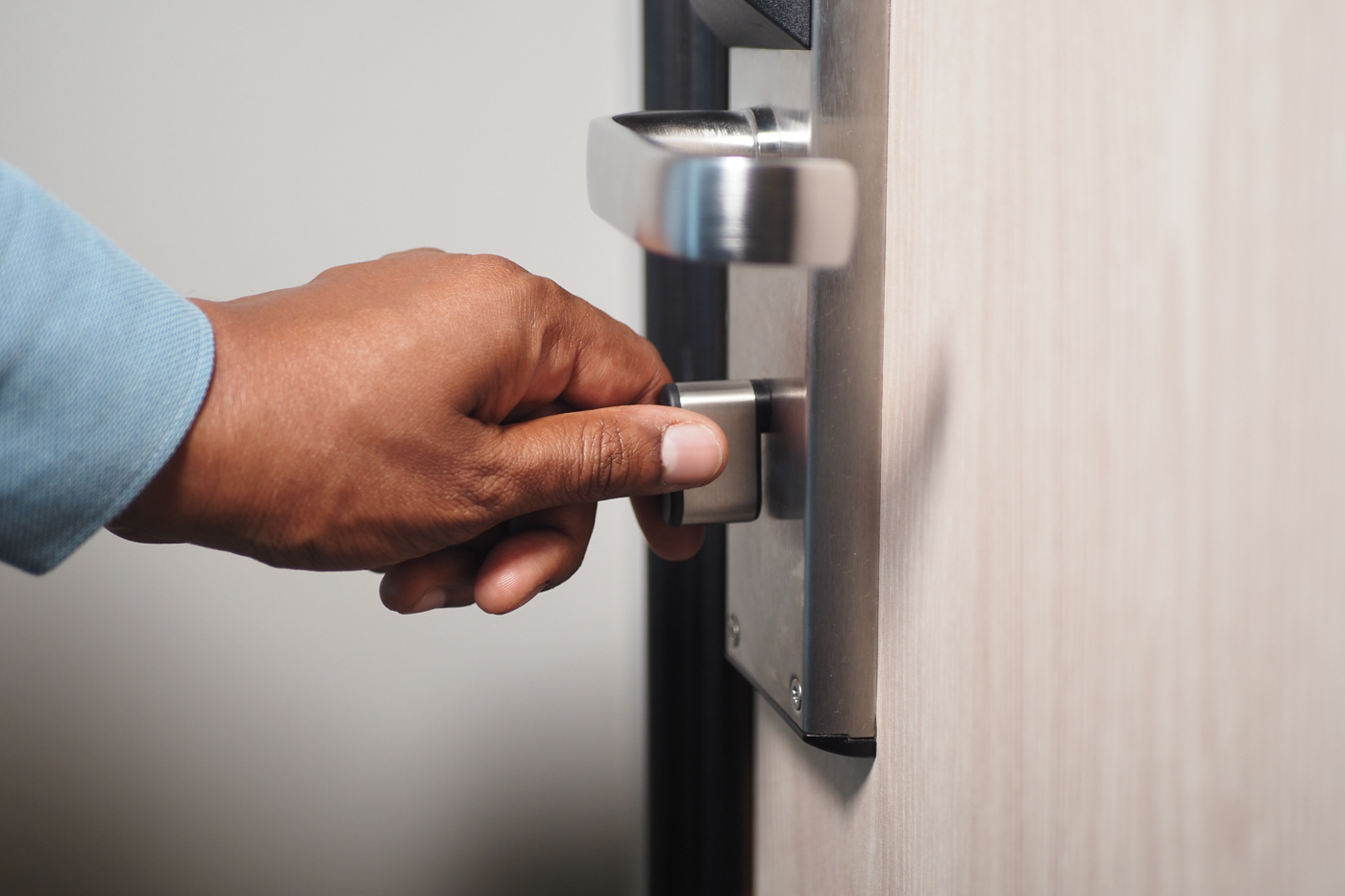 Hand turning front door knob during lock change service
