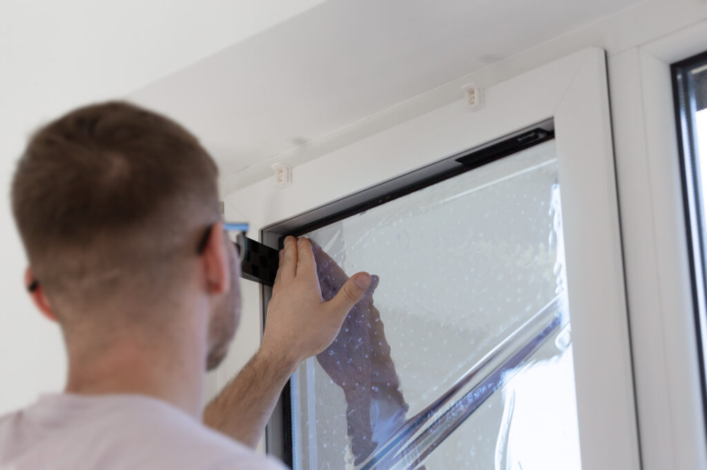 Window insulation film being installed in Canadian home