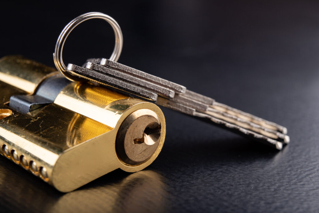 Brass cylinder lock with house keys on black surface
